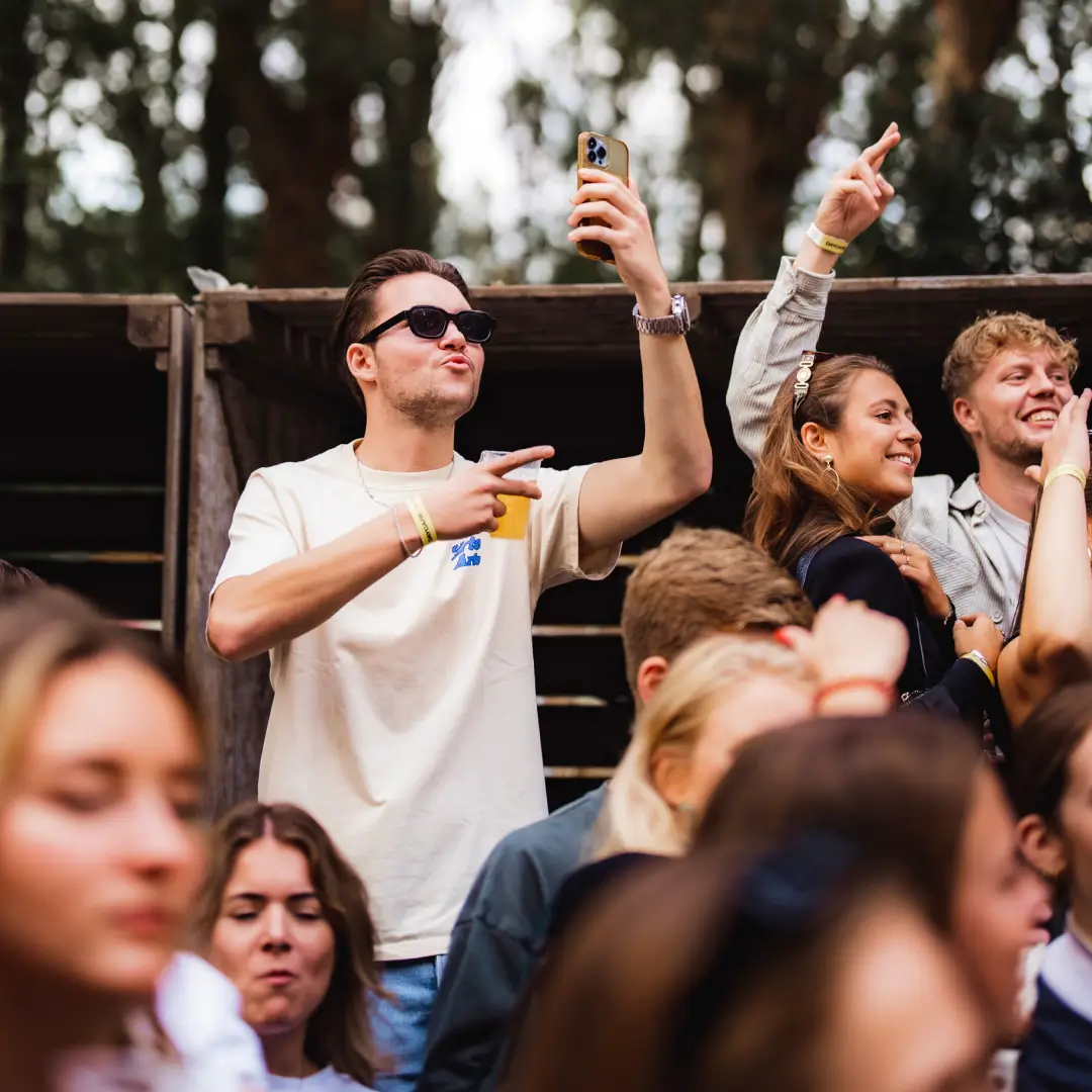 Een levendig buitenevenement met een menigte die het moment vastlegt terwijl een DJ live optreedt op een festival.